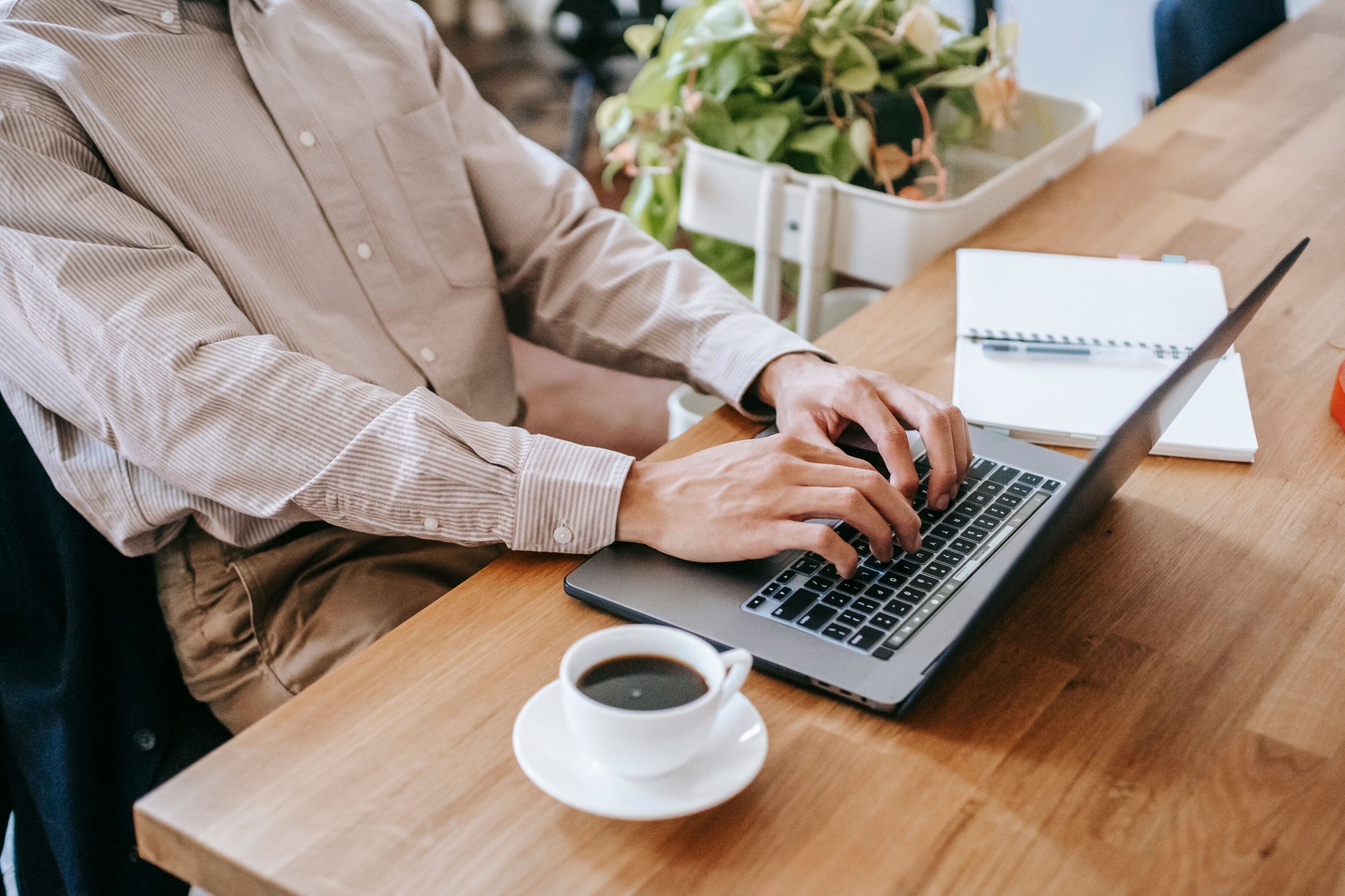Person working on laptop with work supplied coffee in office
