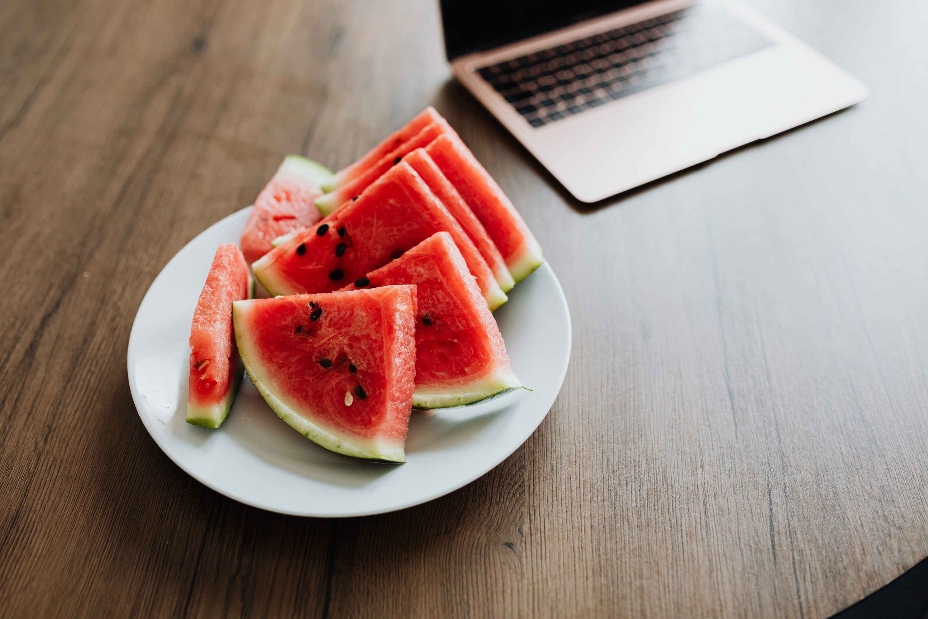 Watermelon sitting on a communal workbench with laptop in sight