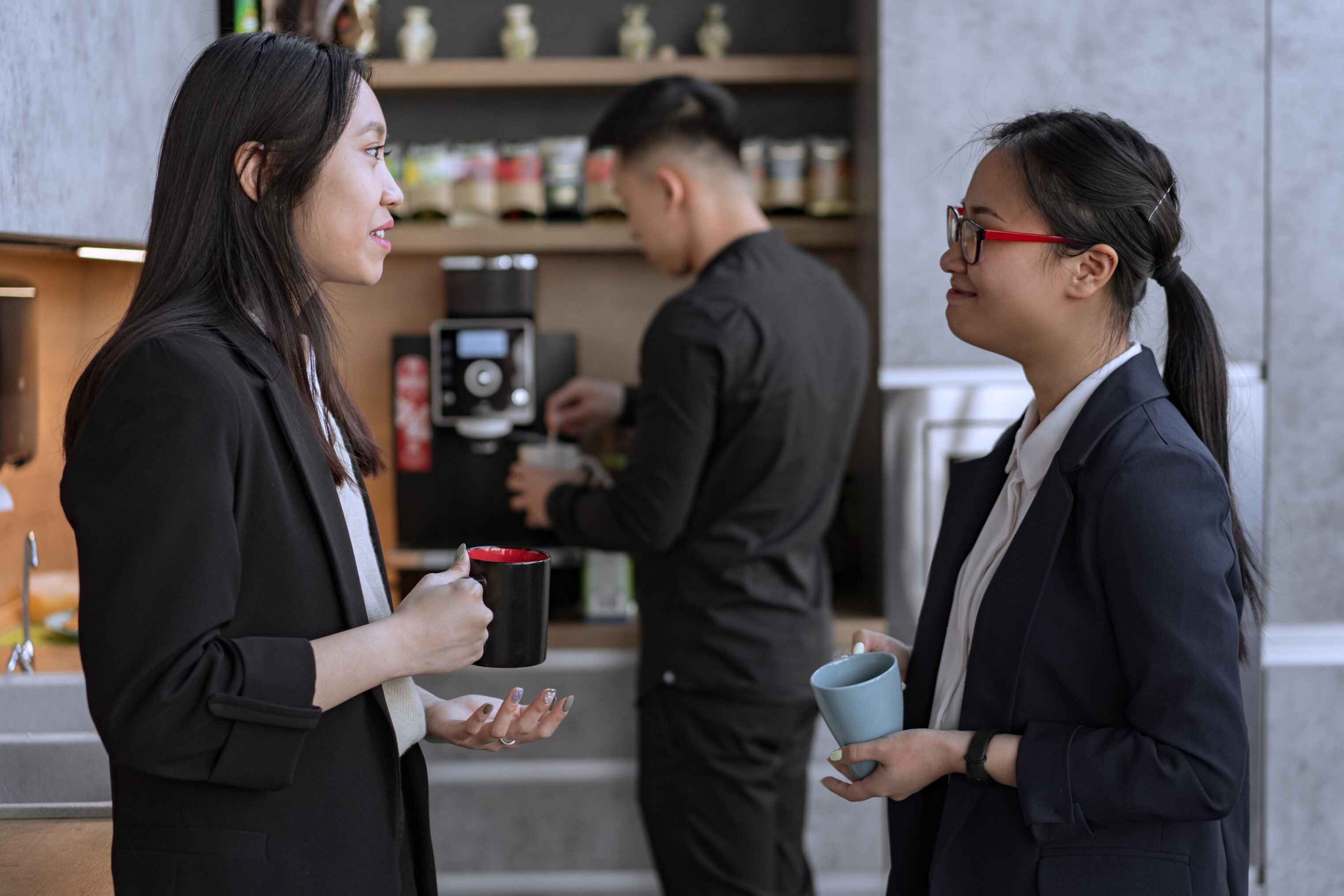 Officeworkers chatting in teamroom while drinking cups of coffee